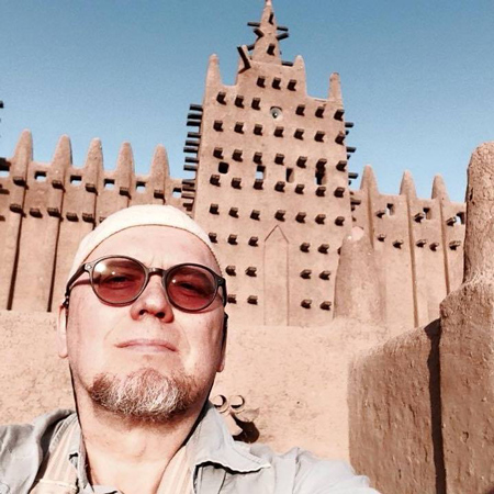 Коля на фоне глиняной мечети в городе Дженне, Мали, 2015 год